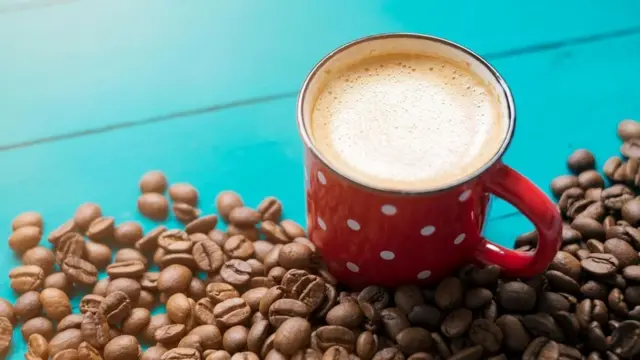 كوب من القهوة بجوار حبوب البن المحمصة