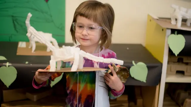 Menina brincando com um dinossauro