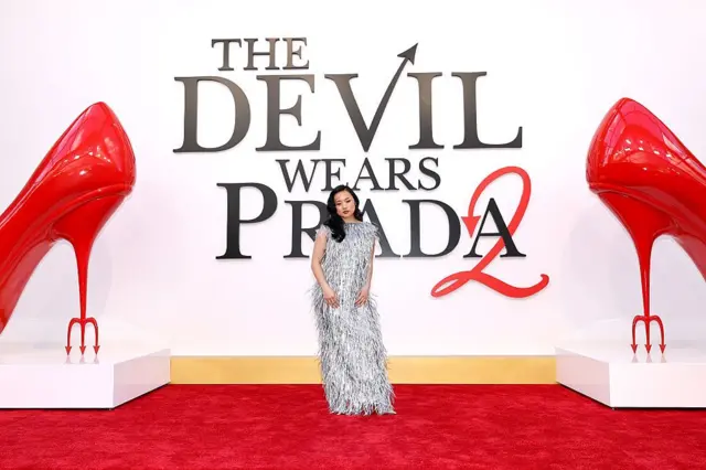 Jin Chao的扮演者沈雨田站在《穿Prada的惡魔2》版畫前。