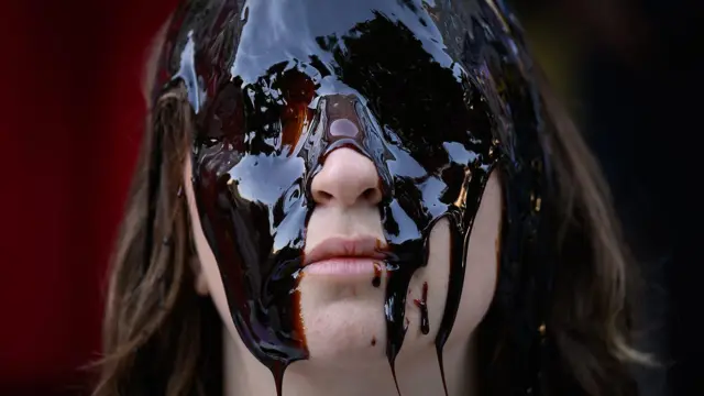 Un mujer con la cara cubierta de una sustancia pegajosa. 