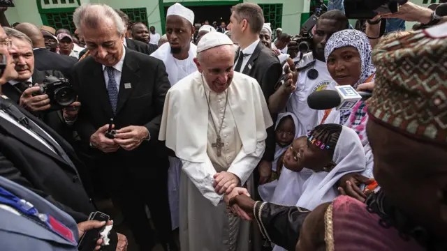 Papa Francisco cumprimentando crianças com a imprensa em volta