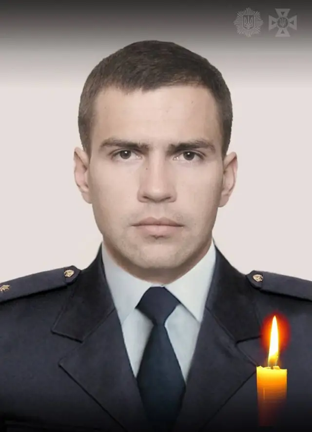 Портрет чоловіка у форменому одязі: темний китель і краватка, нейтральний світлий фон. Обличчя зображене фронтально, без додаткових елементів. У правому нижньому куті — запалена свічка як символ пам’яті.