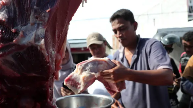 Pekerja memotong daging sapi yang djajakan pada kios pangan murah khusus daging tradisi meugang yang digelar di Banda Aceh, Aceh, Sabtu (09/03).