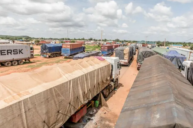 Une longue file de camions fait la queue à la frontière fermée entre le Bénin et le Niger, dans la ville de Malanville, le 18 septembre 2023. Près de la frontière nord du Bénin avec le Niger, des centaines de camions de marchandises bloqués s'étendent sur dix kilomètres ; leurs cargaisons se détériorent et leurs chauffeurs se retrouvent sans le sou après avoir passé des semaines coincés à cette frontière fermée.