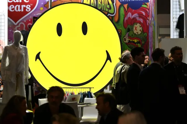 Emoji de rosto sorridente amarelo em exibição durante evento no ExCel, em Londres