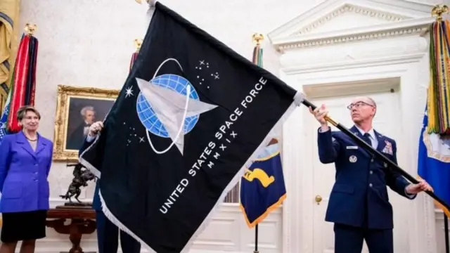 Un militaire en tenue brandit le drapeau des forces spatiales américaines