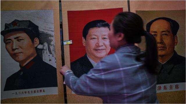 一名妇女在摆放毛泽东和习近平的照片