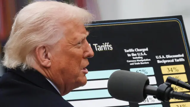 Donald Trump de perfil, frente a una pantalla que muestra la lista de países a los que impondrá aranceles