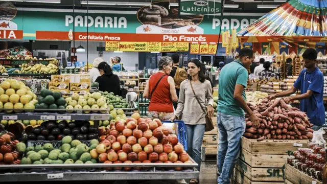 Pessoas na seção de frutas e verduras de um supermercado