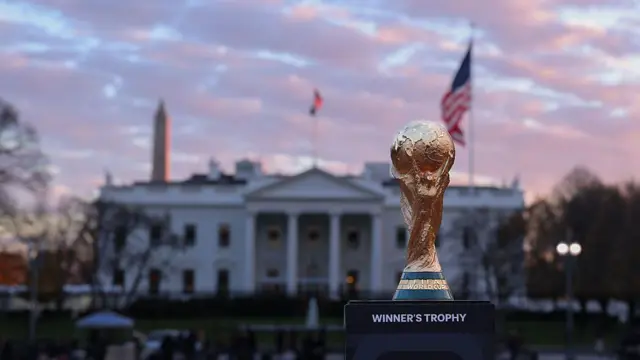El trofeo de la Copa del Mundo se encuentra frente a la Casa Blanca, flanqueado a ambos lados por una bandera de los Estados Unidos y el Monumento a Washington.
