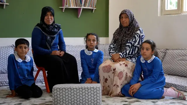 Saadet Maç ve kızları Zehra ile Azra sağ tarafta oturuyor. Yanlarında Necla Matur ve oğlu İbrahim oturuyor. Çocukların üzerinde mavi üniforma var.