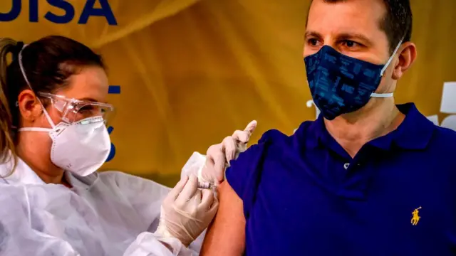 Un voluntario siendo vacunado por una trabajadora de la salud en Porto Alegre, Brasil