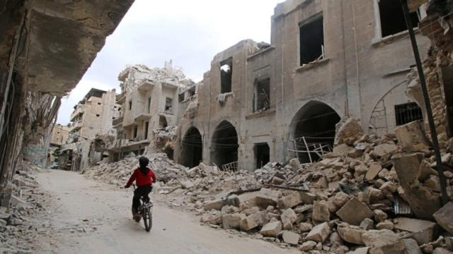 A boy rides a bicycle near damaged buildings in the rebel held area of Old Aleppo, Syria May 5, 2016