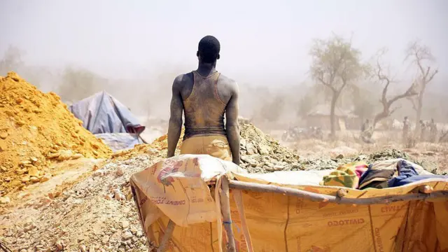 Un homme tourne le dos à la caméra, regardant une mine d’or clandestine au Burkina Faso