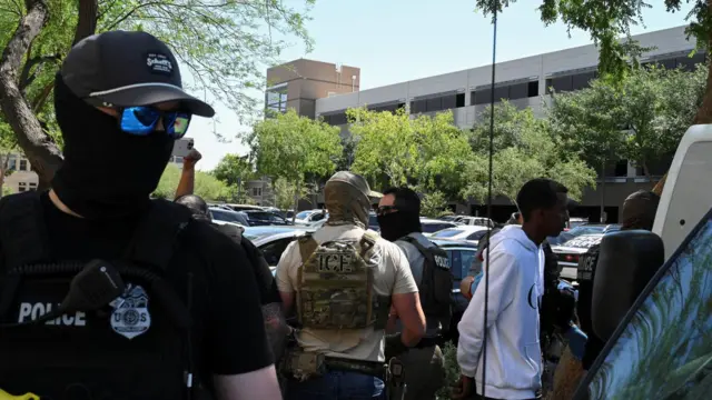 Policiais mascarados, incluindo agentes do HSI e do ICE, levam pessoas sob custódia em um tribunal de imigração em Phoenix, Arizona, EUA, em 21 de maio de 2025.