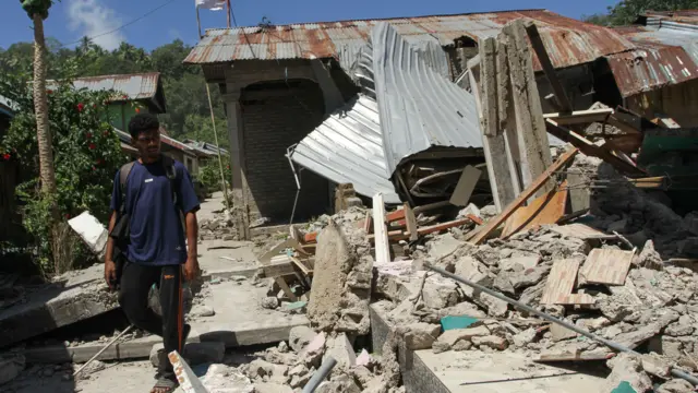 Warga melintas di samping bangunan rumah yang roboh akibat gempa bumi magnitudo 7,7 di Pulau Palue, Kabupaten Sikka, NTT, Rabu (19/8/2026). Gempa bumi pada Sabtu (15/8/2026) tersebut menyebabkan ratusan rumah rusak di pulau berpenduduk sekitar 11.000 jiwa dan berjarak 20-30 kilometer dari pusat gempa.