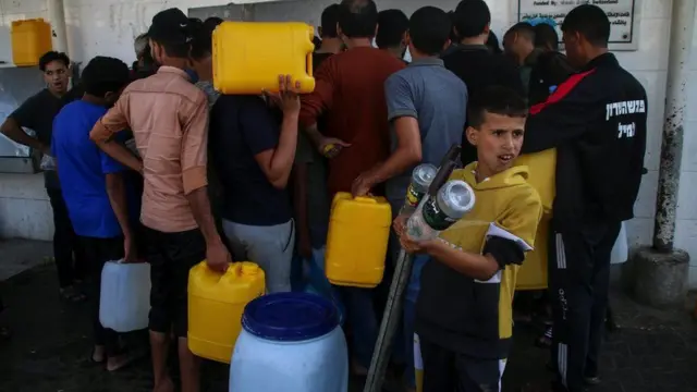 Des Palestiniens remplissent de l'eau à partir de stations d'eau dans la rue à Khan Younis, au sud de la ville de Gaza.