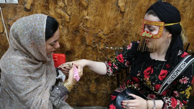 کشیدن نقش و نگار با حنا روی دست یک زن گردشگر در جزیره قشم 