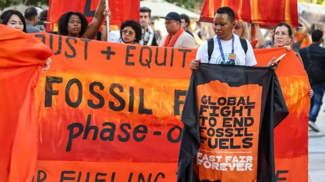 Protestors hold banners outside di COP28 climate conference