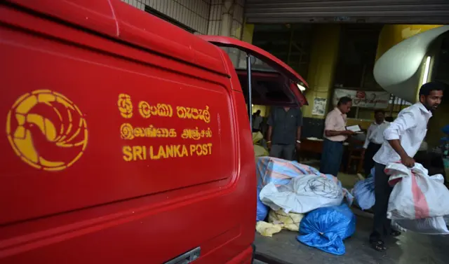 A Sri Lankan postal service's employee loads bags of mail into a vehicle at the General Post Office in Colombo on October 3, 2013.