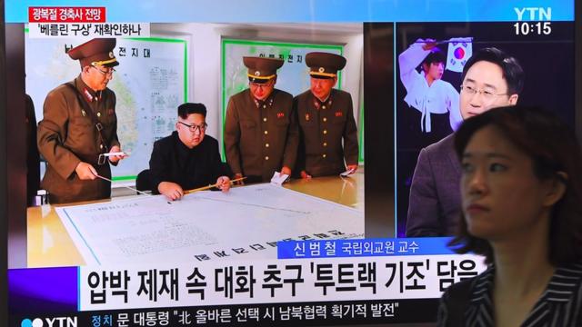 Una mujer pasa en Seúl junto a una pantalla de televisión con la imagen de Kim Jong-un