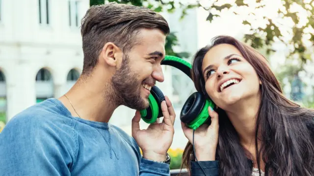 Dos jóvenes escuchando música con los mismo auriculares.