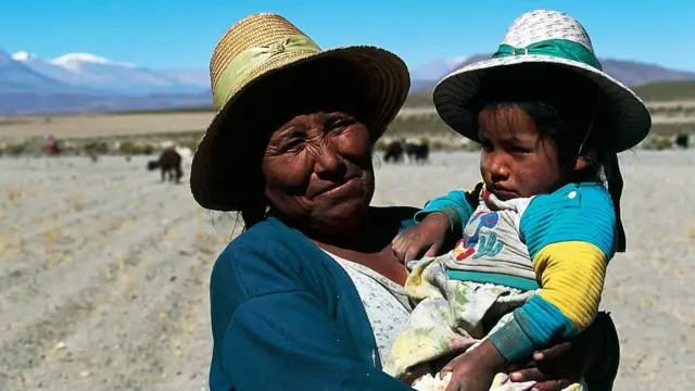 Mujer aymara sostiene a una niña.