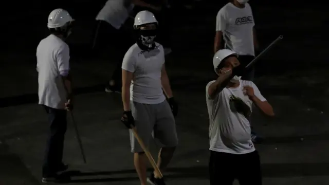 白衣施暴者手持棍棒等武器。