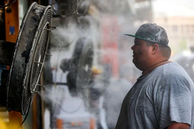 Čovek stoji ispred ventilatora u Bagdadu gde je temperatura dostigla više od 50 stepeni Celzijusa ili 122 stepena Farenhajta.