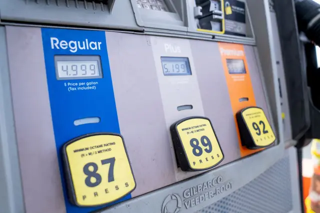 Dispensador de gasolina muestra tres precios, para "regular"de 87 octanos, "más"de 89 octanos, y "de primera calidad"de 92 octanos. Se puede ver que la regular cuesta US$4.999 por galón, la plus US$5.199 y la premium US$5.399.