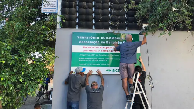 Moradores instalam placa do Quilombo Kédi na fachada da associação