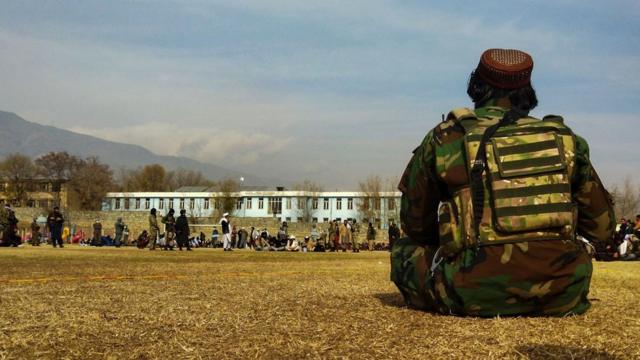 阿富汗帕尔旺省恰里卡尔市一场公开体罚大会上一名塔利班战斗人员坐在草坪上（8/12/2022）