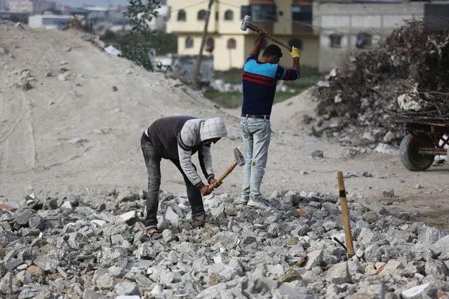 Pekerja di sebuah pabrik yang mendaur ulang puing-puing rumah yang hancur