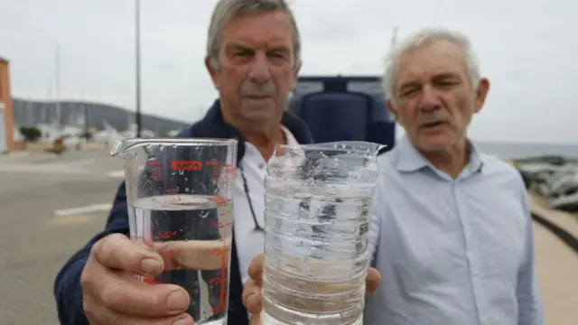 dvojica muškaraca drže čase sa prerađenom i morskom vodom