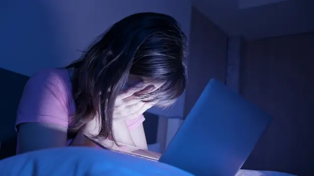 ল্যাপটপের সামনে একজন বিব্রত ও হতাশাগ্রস্ত নারী