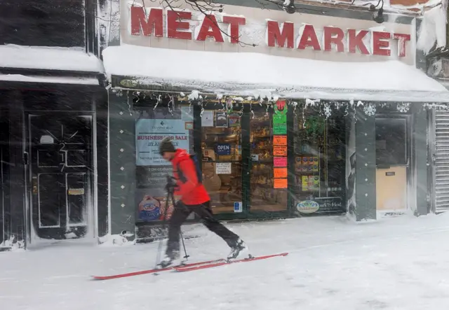  Человек на лыжах бежит по одной из торговых улиц Нью-Йорка мимо закрытых магазинов и лавок.