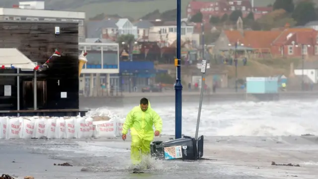 Мужчина укладывает мешки с песком в Суонедже, графство Дорсет