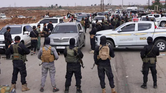 عناصر من قوى الأمن الداخلي يقفون حراسًاً عند حاجز أمني لمنع مقاتلين بدو من التقدم باتجاه السويداء، عقب تجدد الاشتباكات بين مقاتلين بدو ومسلحين دروز، رغم إعلان وقف القتال، في بلدة ولغا، محافظة السويداء، سوريا، 20 يوليو/تموز 2025. 