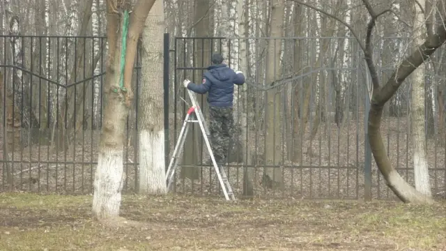 Мужчина красит забор