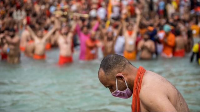 Homem usando máscara entra no Rio Ganges, na Índia