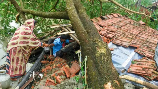 পশ্চিমবঙ্গের মেদিনীপুরে এক বিধ্বস্ত বাড়ি থেকে তৈজসপত্র উদ্ধারের চেষ্টা করছে এক পরিবার।
