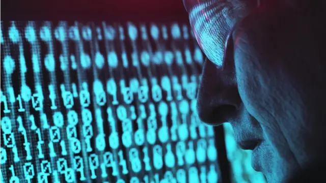 Мужчина в очках смотрит на экран с двоичным кодом - стоковая фотография