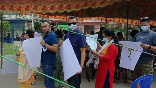 मतपत्र बोकेर मतदान गर्न जान लागेका मतदाताहरू