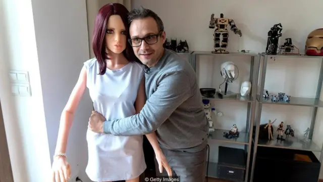 سرگئی سانتوز یکی از اختراعاتش را بغل می‌کند، رباتی برای روابط جنسی که به عقیده او می‌تواند حافظ روابط زناشویی باشد