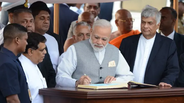 India's Prime Minister Narendra Modi (C) is watched by Sri Lankan Prime Minister Ranil Wickremesinghe (R) and other officials after signing the 'Golden Book' after arriving at Bandaranaike International Airport in Colombo on May 11, 2017, for a visit to Sri Lanka. / AFP PHOTO / LAKRUWAN WANNIARACHCHI (Photo credit should read LAKRUWAN WANNIARACHCHI/AFP/Getty Images