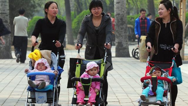 Three Chinese mothers walk with their children in prams