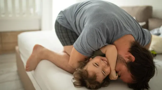 पिता अपनी बेटी को खेलते हुए कसकर गले लगाता है