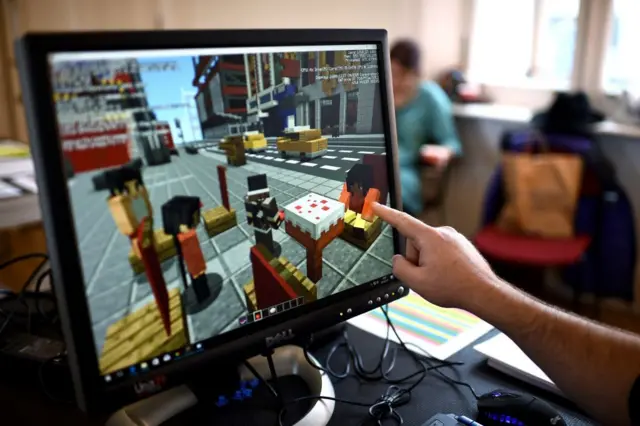 Bilgisayar ekranındaki Minecraft oyununu işaret bir el