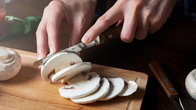 Kesme tahtasında bıçakla dilimlenen mantarlar.