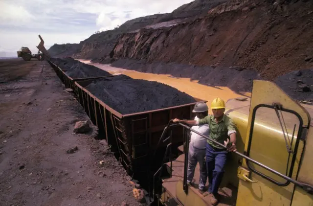 Unos trabajadores venezolanos en un tren cargado de mineral de hierro en el estado Bolívar.